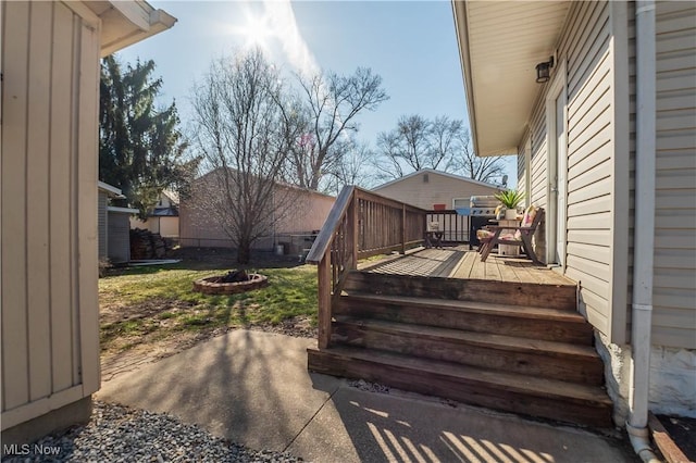 wooden deck with a patio, fence, and a grill