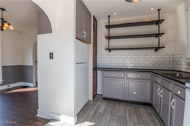 kitchen with dark countertops, gray cabinets, wood finished floors, and arched walkways