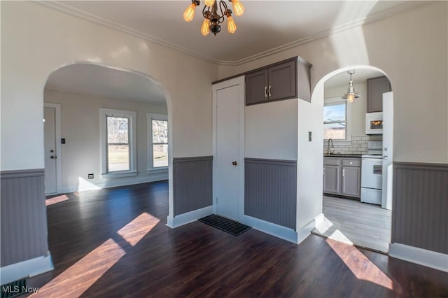 interior space with a wainscoted wall, arched walkways, and a sink