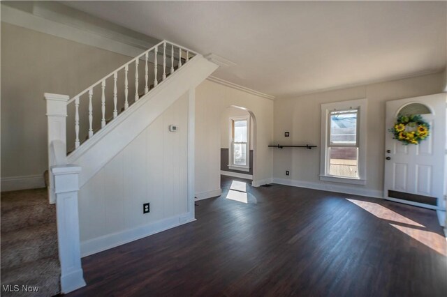 foyer entrance with arched walkways, stairs, baseboards, and dark wood-style flooring