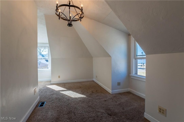 additional living space with carpet, visible vents, baseboards, an inviting chandelier, and lofted ceiling