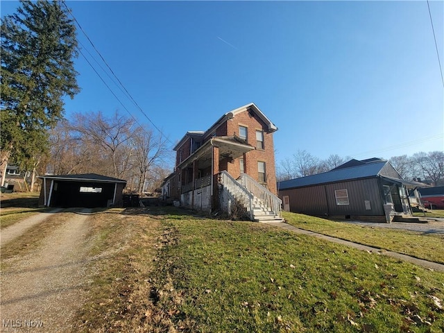 view of side of home with brick siding, a lawn, an outdoor structure, and dirt driveway