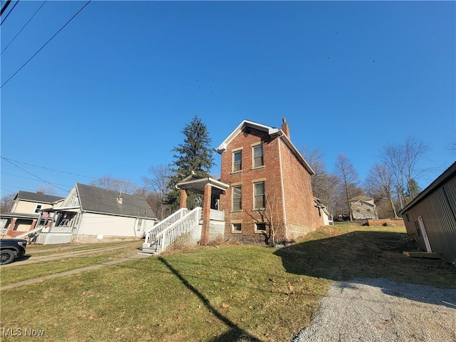 view of front of house featuring a front lawn, brick siding, and a chimney