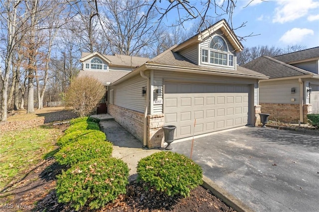 view of side of home featuring an attached garage, driveway, and a shingled roof