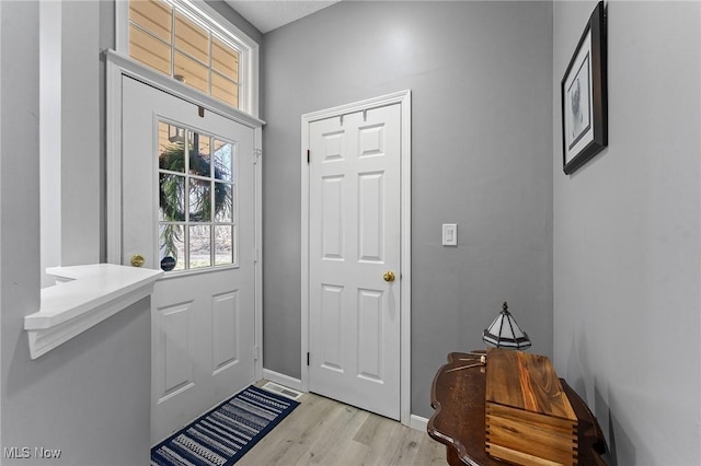 doorway to outside with light wood-style floors and baseboards