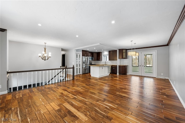 unfurnished living room featuring dark wood-style floors, recessed lighting, an inviting chandelier, and baseboards