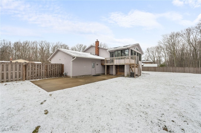 rear view of house featuring a fenced backyard, stairs, a sunroom, a wooden deck, and a chimney