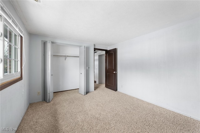 unfurnished bedroom featuring light colored carpet, a closet, and a textured ceiling