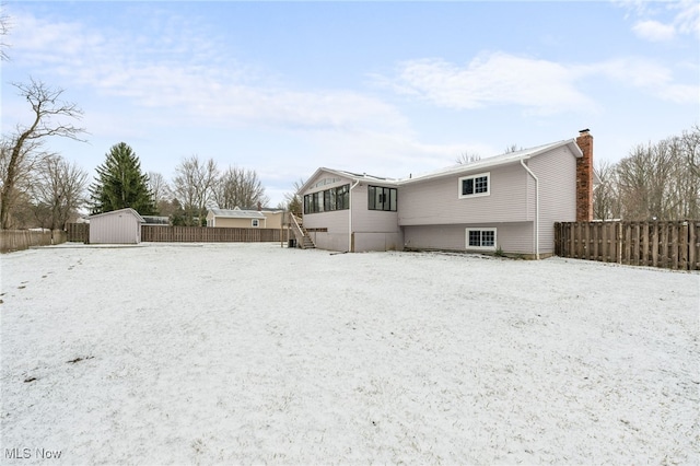 rear view of house with a storage shed, fence, an outdoor structure, and a chimney