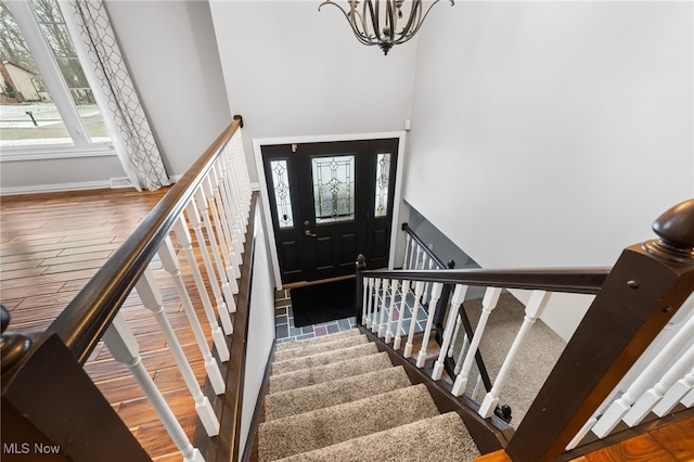 entryway with baseboards, stairs, an inviting chandelier, and wood finished floors