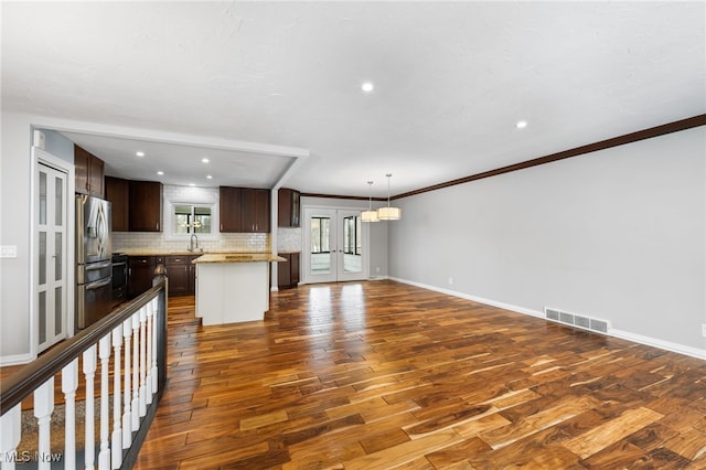 kitchen featuring visible vents, dark brown cabinets, light countertops, french doors, and a sink