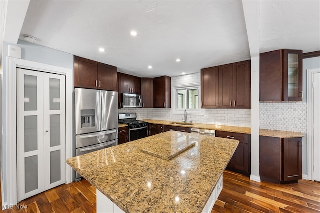 kitchen featuring a sink, a kitchen island, appliances with stainless steel finishes, and dark wood finished floors