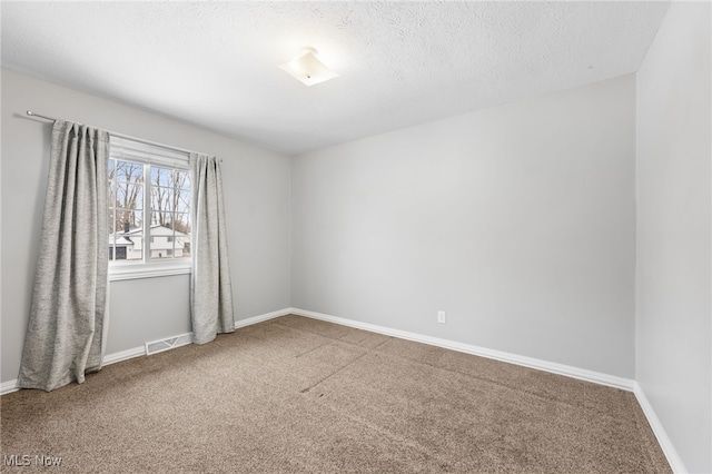 carpeted empty room with visible vents, baseboards, and a textured ceiling