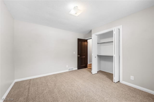 unfurnished bedroom with baseboards, visible vents, carpet floors, and a closet