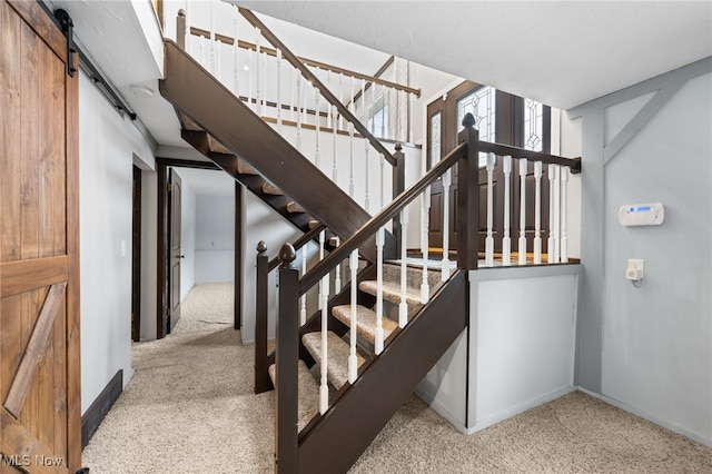 stairway with baseboards, carpet, and a barn door