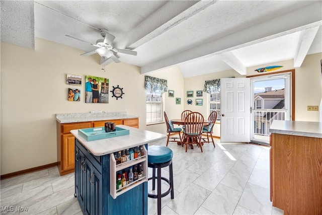 kitchen with blue cabinetry, a kitchen breakfast bar, plenty of natural light, and light countertops