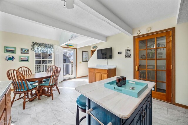 dining area with baseboards, beam ceiling, a textured ceiling, and marble finish floor