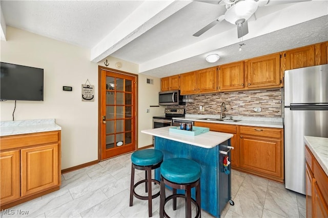 kitchen featuring brown cabinets, appliances with stainless steel finishes, marble finish floor, and a sink