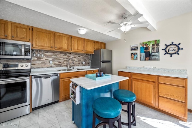 kitchen with backsplash, light countertops, brown cabinets, appliances with stainless steel finishes, and a sink