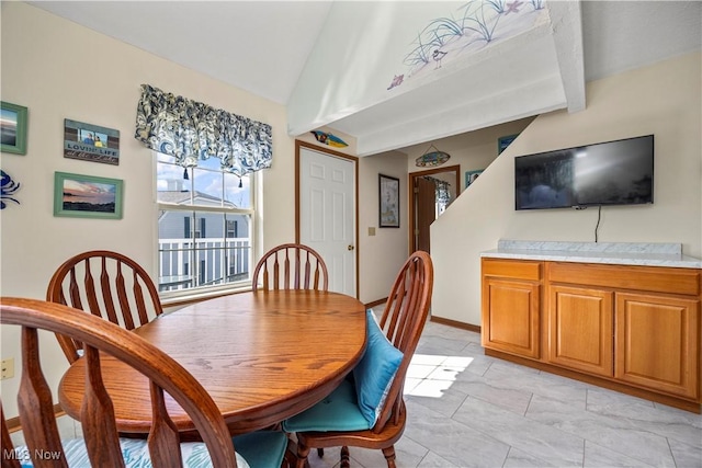 dining space featuring vaulted ceiling with beams