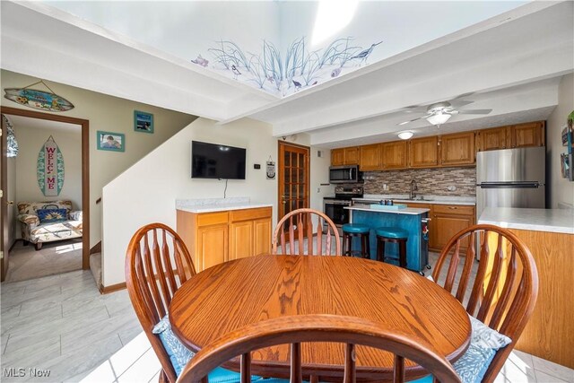 dining room with beam ceiling and a ceiling fan