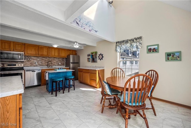 dining area with beamed ceiling, baseboards, and ceiling fan