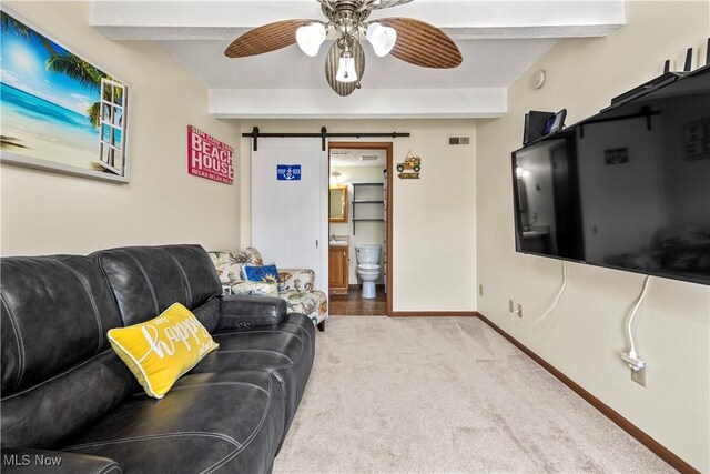 carpeted living room featuring visible vents, beam ceiling, a ceiling fan, a barn door, and baseboards