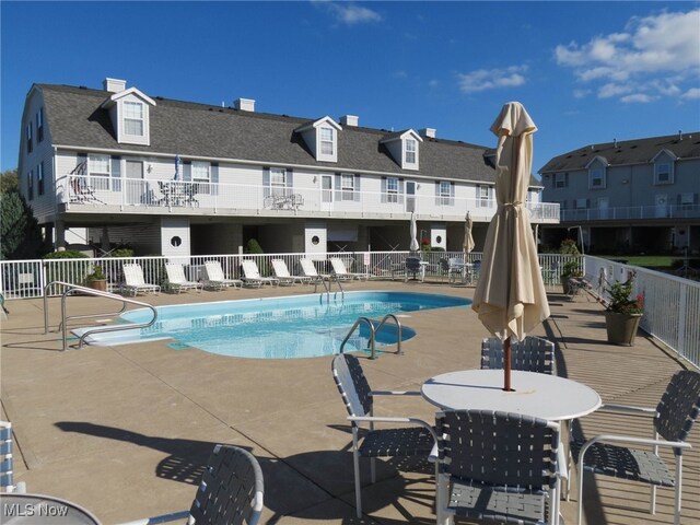 pool featuring a patio, fence, and a residential view