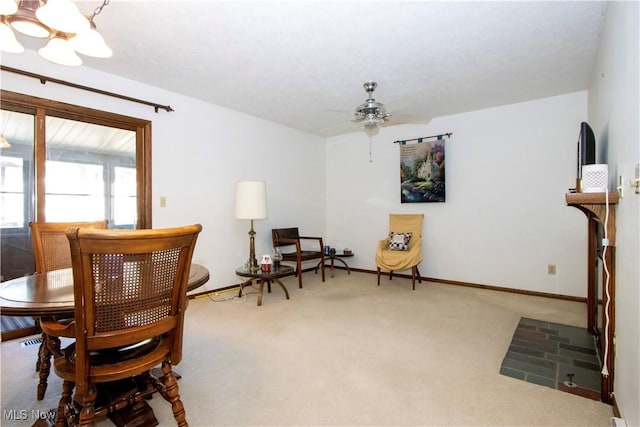 carpeted dining space with ceiling fan with notable chandelier and baseboards