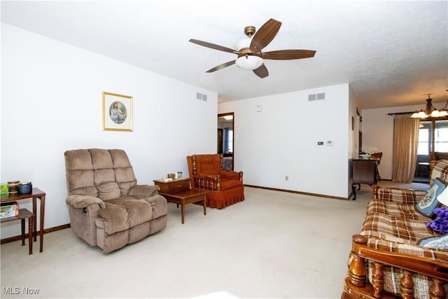 living room featuring visible vents, baseboards, carpet flooring, and ceiling fan with notable chandelier