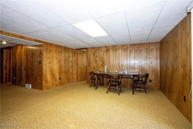 carpeted dining area with visible vents and wood walls