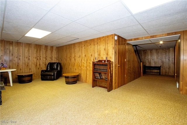 unfurnished room with stairway, wood walls, a paneled ceiling, and carpet