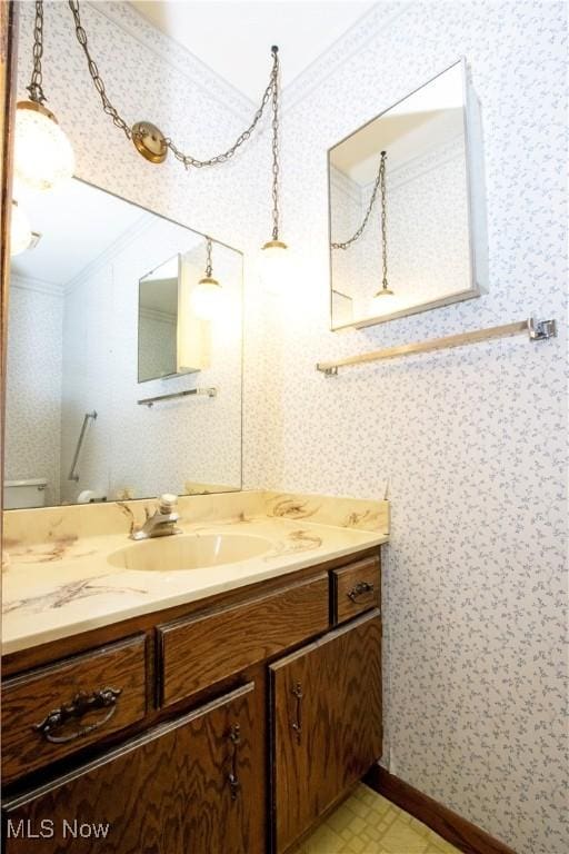 bathroom featuring tile patterned floors, ornamental molding, wallpapered walls, baseboards, and vanity