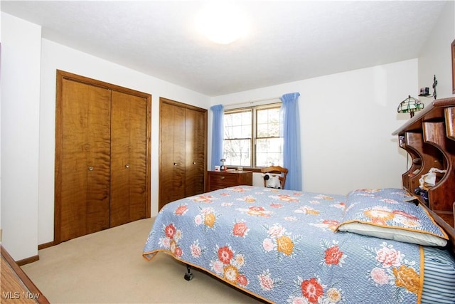 carpeted bedroom with baseboards and two closets