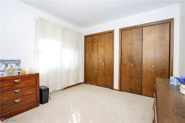 bedroom with two closets and light carpet