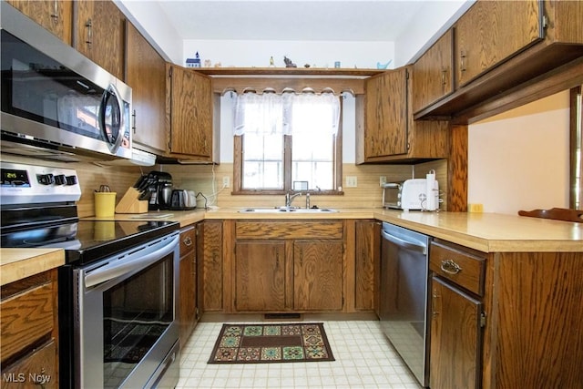 kitchen with decorative backsplash, appliances with stainless steel finishes, light countertops, and a sink