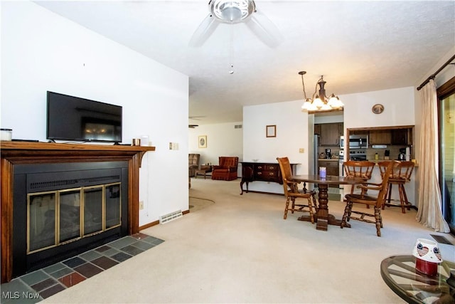 dining room featuring visible vents, baseboards, a fireplace with flush hearth, carpet flooring, and a ceiling fan