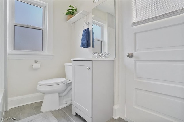 bathroom with baseboards, toilet, wood finished floors, and vanity