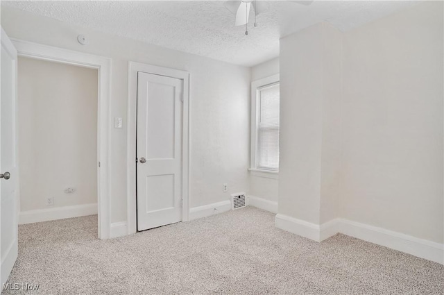 unfurnished bedroom with visible vents, baseboards, carpet, a textured ceiling, and a ceiling fan