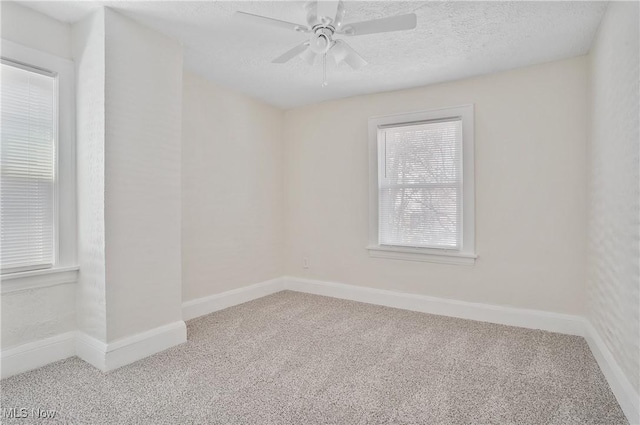 carpeted spare room featuring ceiling fan, a textured ceiling, and baseboards