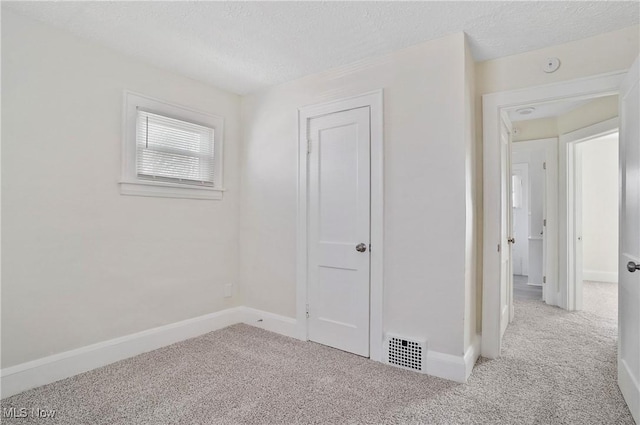 spare room with visible vents, carpet floors, and a textured ceiling