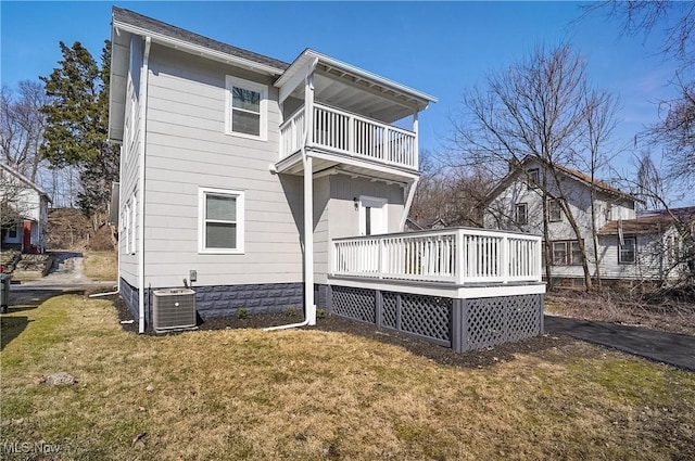 back of property with cooling unit, a yard, and a balcony