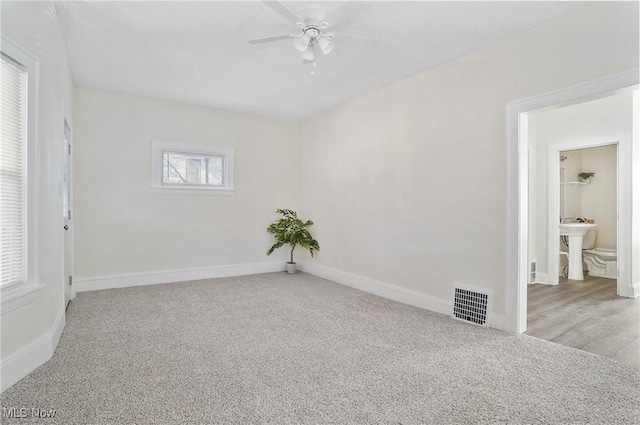 carpeted spare room featuring visible vents, ceiling fan, and baseboards