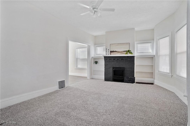 unfurnished living room featuring carpet, visible vents, baseboards, ceiling fan, and a brick fireplace