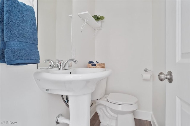 half bath featuring baseboards, toilet, and wood finished floors