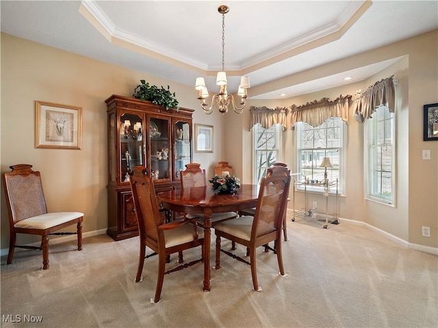 dining room featuring a chandelier, light colored carpet, baseboards, and a tray ceiling