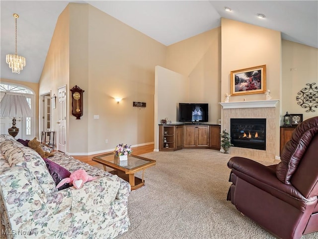 living area with baseboards, high vaulted ceiling, a tile fireplace, light carpet, and a notable chandelier