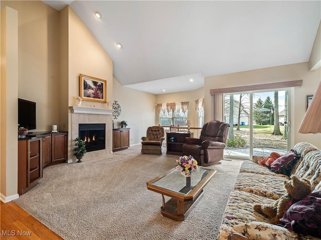 living area with baseboards, a tiled fireplace, light carpet, recessed lighting, and high vaulted ceiling