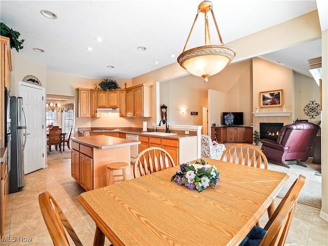 dining room featuring lofted ceiling, light tile patterned floors, recessed lighting, and a lit fireplace