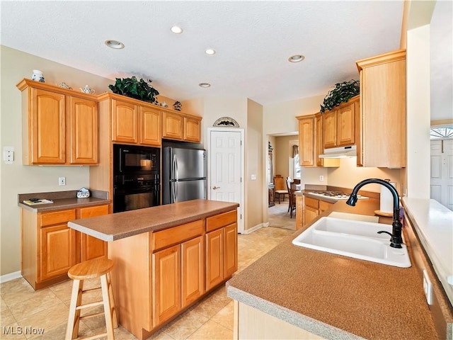 kitchen with a center island, under cabinet range hood, recessed lighting, black appliances, and a sink